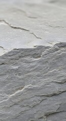 Close-up of a textured, layered stone surface showcasing natural cracks and roughness in a neutral color palette