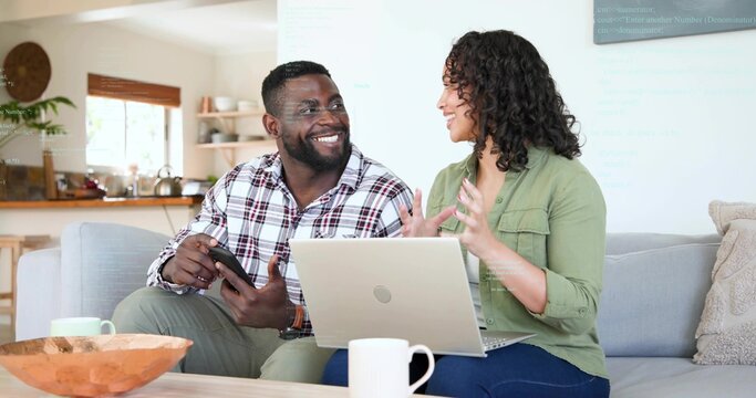 Sitting couple wearing plaid and green shirts chatting in living room with laptop, smartphone