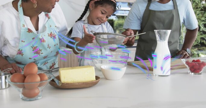 Sifting family trio wearing aprons using metal sieve into large glass mixing bowl at home counter