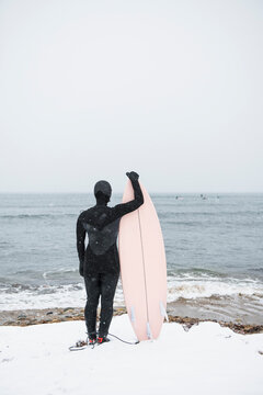 Solo Woman with surfboard going to surf in the snow