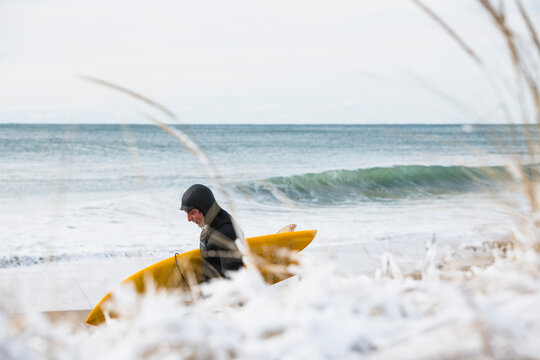 Solo man on a winter beach going surfing