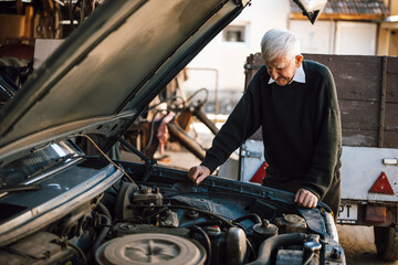 Elderly man inspecting an engine in a garage