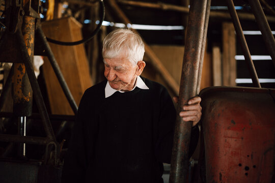 Elderly man in black sweater standing in a rustic barn