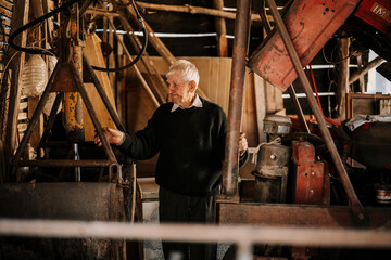 Elderly man working in a rustic workshop with machinery