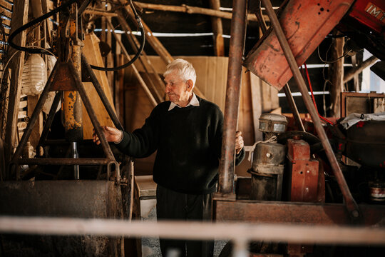 Elderly man working in a rustic workshop with machinery