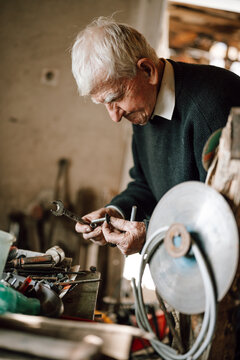Elderly man working on tools in a cluttered workshop