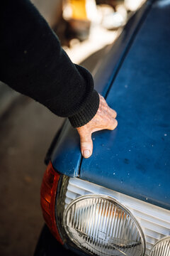 Hand touches the hood of an old blue car