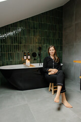 Fototapeta premium Woman in pajamas sitting in modern luxury bathroom