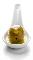 A close-up of a green placed in a white ceramic spoon with a plain white background, highlighting the fruit's smooth surface and fresh appearance