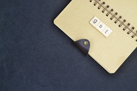 "Black backdrop text space, a marked book, and a building block-style GST word For abstract concepts and positive philosophy
 - Powered by Adobe