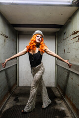 A Queer Performer With Striking Orange Hair Poses Confidently in an Elevator