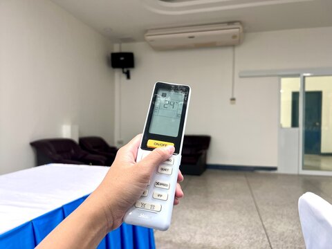 close up a hand holding a Haier air conditioner remote control and adjusting the temperature. Concept of cooling, comfort, smart home technology, and modern lifestyle , 22 November 2025 , Thailand.