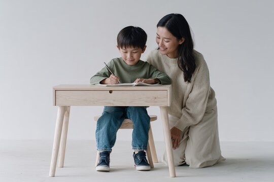 Mother helping son with homework at wooden desk indoors
