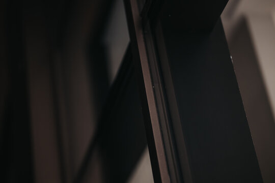 A close-up shot of a sleek black metal frame and glass panel, emphasizing modern architecture and minimalism. This abstract detail conveys sophistication and urban design.