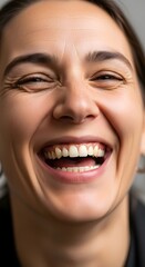 Close-up of a woman with a joyful expression, smiling widely and showing her teeth, capturing happiness and positive emotion in a natural setting