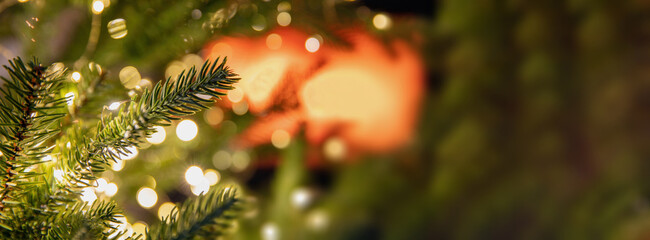 Close-up of Christmas tree branches featuring glowing lights creating the warm indoor holiday...