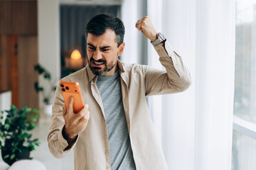 Frustrated man expressing anger while using smartphone