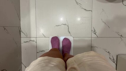 A young girl stands on an electronic floor scale to measure excess weight at home video 4k