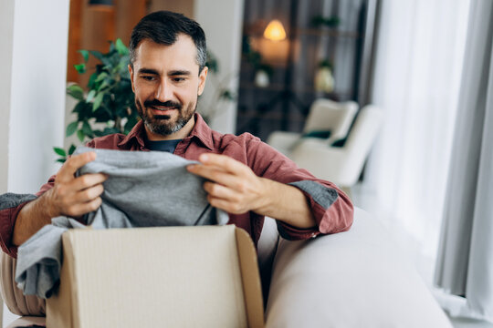Happy man unboxing clothes from online shopping delivery
