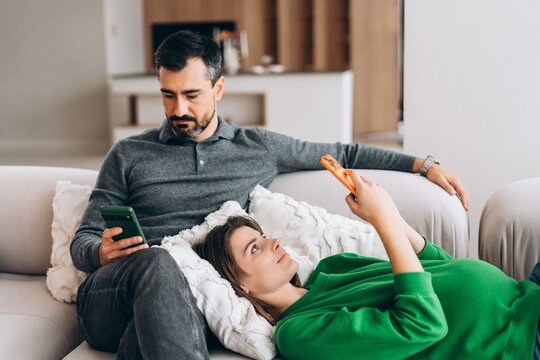 Couple ignoring each other while using smartphones on sofa - Powered by Adobe