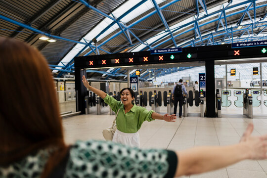 Happy friends greeting with hug at train station arrival