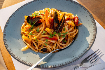 Linguine with seafood and vegetable on plate with spoon and fork.