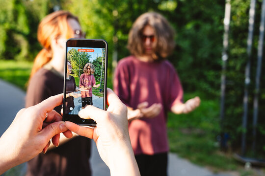 Group filming social media content with smartphone outdoors in sunlight