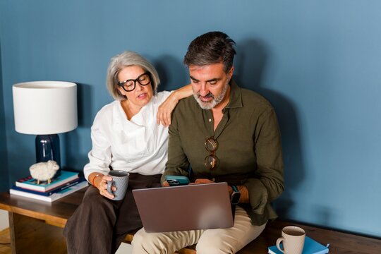 Couple at home using laptop and coffee cup showing teamwork and bonding