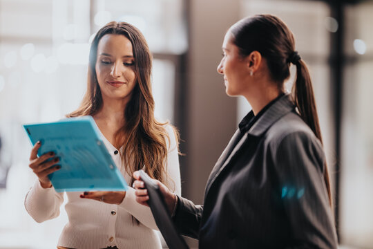 Two people share a moment of teamwork in a contemporary office, examining a bright blue folder as they collaborate on a plan. A candid, constructive scene of business communication and partnership.