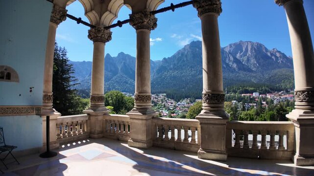 Ornate stone columns framing the stunning panoramic landscape of the Bucegi Mountains and the scenic Busteni town below from the historic Cantacuzino Castle in Transylvania, Romania
