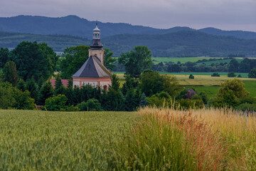 Rural landscape with a church and mountains in the background.