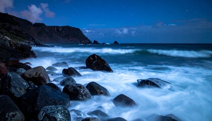 Obraz premium Rocky shore bathed in moonlight, with waves crashing against the rocks under a night sky dotted with stars