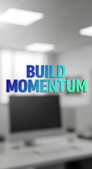 A modern office environment featuring a motivational message with the words 'Build Momentum' displayed in colorful 3D letters on a blurred background of desks and computers