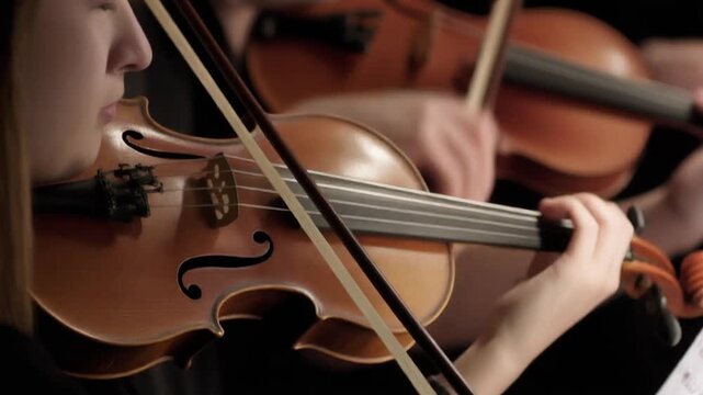 Young violinist playing a classical string musical instrument with a bow in concert. Close-up of a Musical Instrument Being Played (Violin Bow)