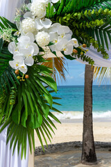 Bathed in sunlight, the wedding pagoda blooms with white orchids and silk, overlooking the turquoise Caribbean Se