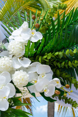 A floral masterpiece of Phalaenopsis aphrodite orchids and tropical leaves captures the essence of island romance