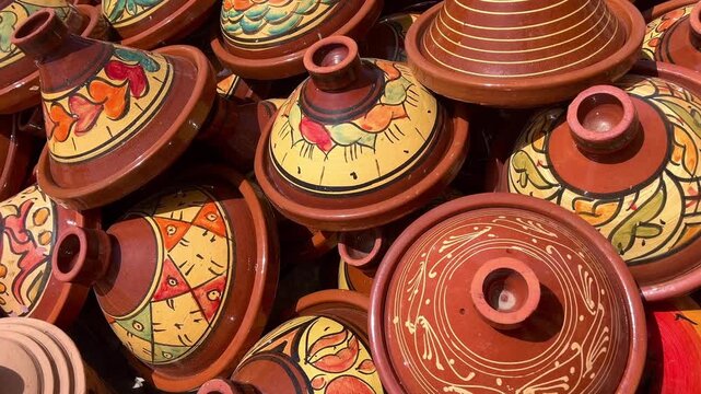 Handmade unglazed terracotta tagines or tajines drying under the sun outdoors at a pottery workshop in Marrakech, Morocco, representing the local craft and gastronomy of North Africa