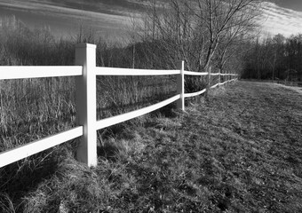 A white plastic fence on the plot boundary in a black and white photograph.