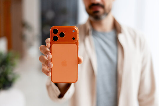 Kyiv, Ukraine - October 22th, 2025: iPhone 17 Pro Max Orange, back view. Man holding an orange smartphone, showing a contemporary Apple device