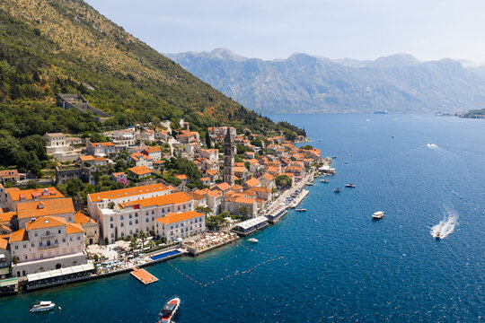 Aerial view of terracotta rooftops cascade down to the shimmering Adriatic Sea, nestled beside the iconic Church of St. Nikola, Perast, Kotor Municipality, Montenegro.