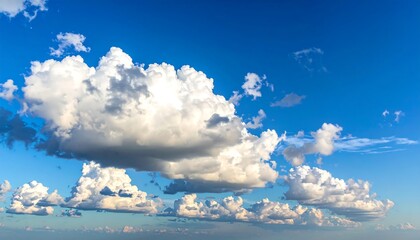 A vibrant, expansive daytime sky filled with fluffy, white cumulus clouds against a brilliant azure backdrop. Sunlight illuminates the scene