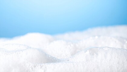 Close-up of fluffy white soap bubbles on a bright blue background clean texture