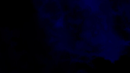 Mysterious swirling deep blue smoke or clouds creating an abstract dark background with ethereal wisps of light