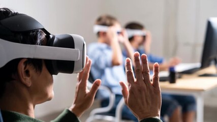 Adult using virtual reality headset with hands raised in modern classroom while students learn with wearable tech, immersive education and digital skills training in a technology lab setting - Powered by Adobe