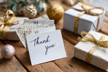 Thank you card with wrapped gifts and ornaments on wooden table