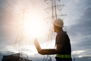 A man in a safety vest stands in front of a power line