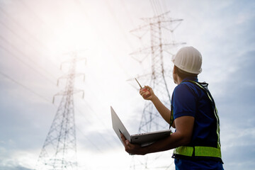 A man in a safety vest stands in front of a power line