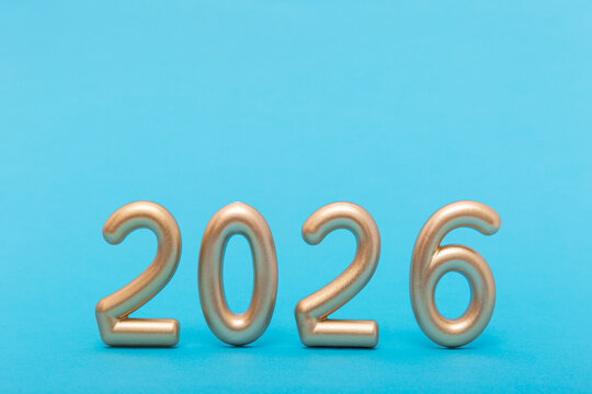 Golden numbers forming 2026 on blue background. Symbol of the new year, future, time and upcoming opportunity. Copy space