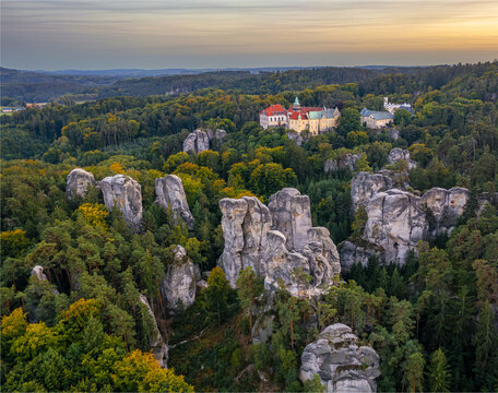 Aerial view of the castle perched atop sandstone formations amidst a sea of autumnal forest hues, a symphony of nature and architecture, Turnov, Liberec Region, Czechia.