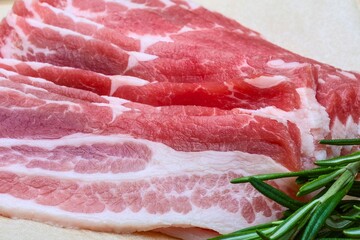 Fresh raw pork belly slices with rosemary, perfect for cooking